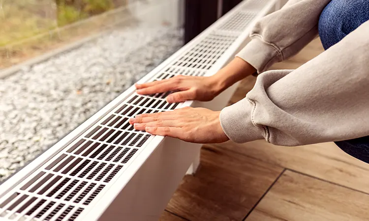 Une femme met ses mains sur un radiateur